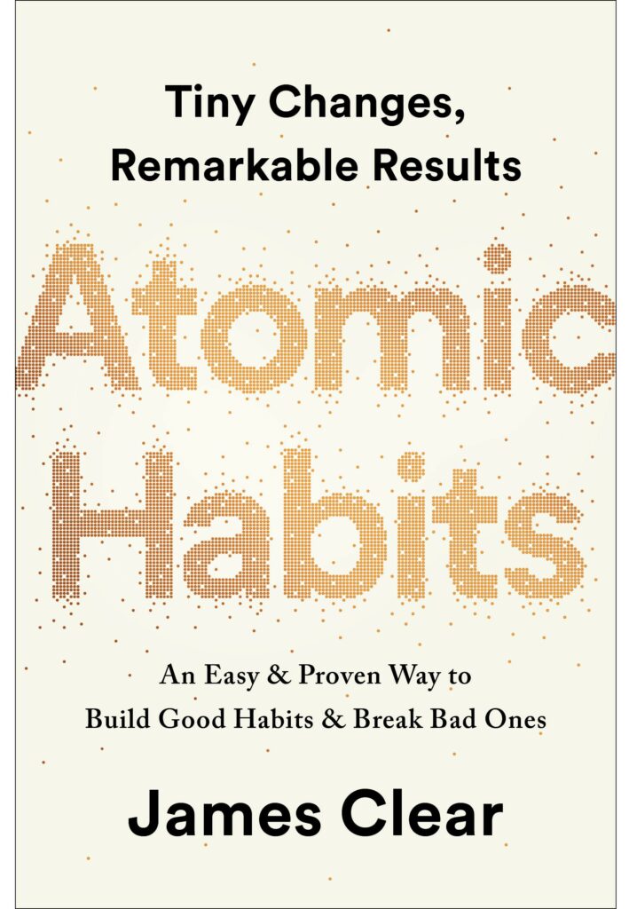 Iconic book cover of Atomic habits written in golden over a pale white background