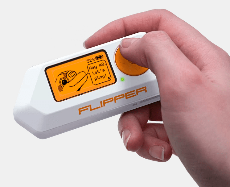 Flipper zero a hacking tool with a orange colored dolphin on the screen, held in the hand.