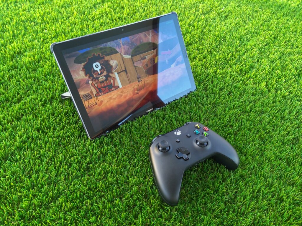 xbox controller on a grass and video game being played on a tablet